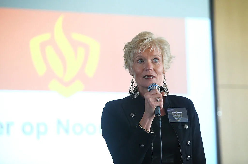 Ilone Blaauw houdt een presentatie voor een veiligheidsregio, met op de achtergrond een brandweer-vlamlogo.